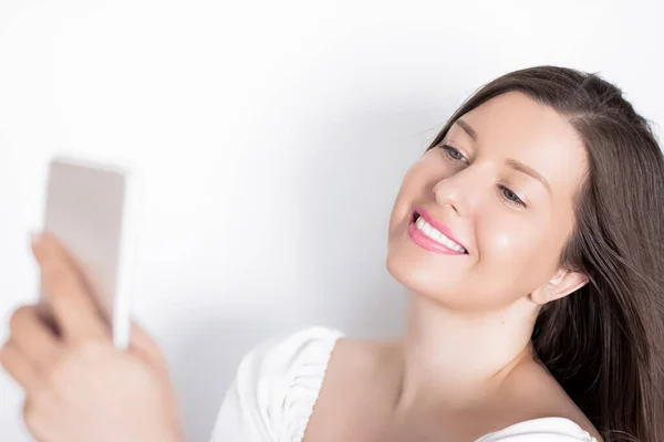 Happy smiling woman with smartphone having video call or taking selfie, portrait on white background. People, technology and communication concept — Stock Photo, Image