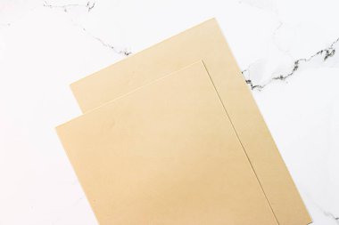 Beyaz mermer arka plan üzerine bej renkli A4 kağıtları ofis kırtasiyesi düz yatak, lüks markalaşma yatağı ve model kimlik tasarımı