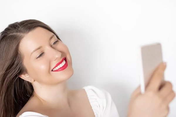 Happy smiling woman with smartphone having video call or taking selfie, portrait on white background. People, technology and communication concept — Stock Photo, Image