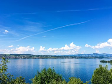 Idyllic İsviçre manzarası, Wollerau 'daki Zürih Gölü manzarası, İsviçre' deki Schwyz kantonu, Zürih, dağlar, mavi su, gökyüzü yaz doğası ve seyahat yeri olarak idealdir.