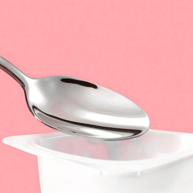Yoğurt kabı ve pembe arka planda gümüş kaşık yoğurt kremalı beyaz plastik kap sağlıklı beslenme ve beslenme dengesi için taze süt ürünü.