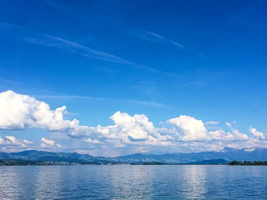 Idyllic İsviçre manzarası, Richterswil, İsviçre 'deki Zürih Gölü manzarası, dağlar, Zürih' in mavi suyu, yaz doğası ve seyahat merkezi olarak gökyüzü, manzaralı sanat baskısı için ideal.