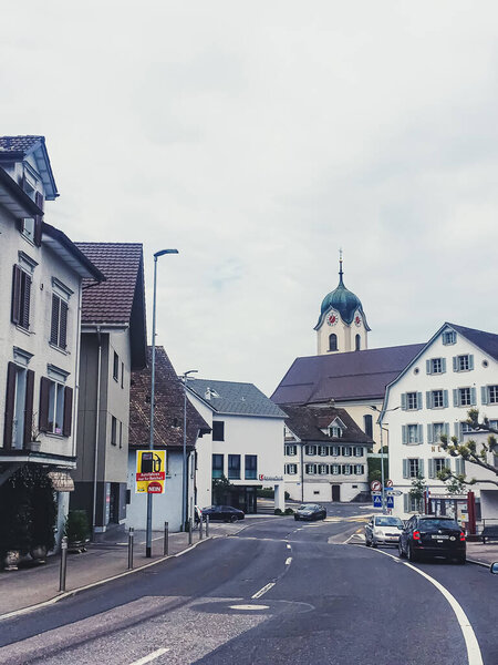 Wollerau, canton of Schwyz, Switzerland circa June 2021: Historic buildings, church and houses on street, Swiss architecture and real estate