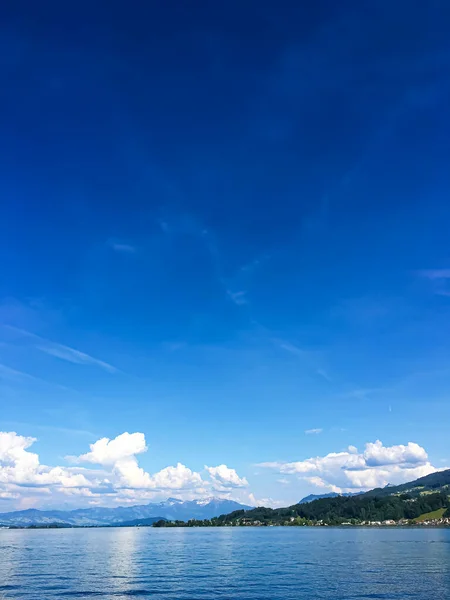 Idyllic İsviçre manzarası, Richterswil, İsviçre 'deki Zürih Gölü manzarası, dağlar, Zürih' in mavi suyu, yaz doğası ve seyahat merkezi olarak gökyüzü, manzaralı sanat baskısı için ideal. — Stok fotoğraf