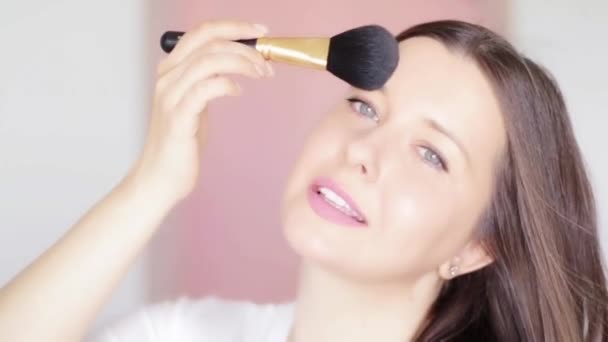 Kvinna med kosmetisk borste tillämpa makeup och leende, skönhet ansikte porträtt av kaukasisk kvinnlig modell på rosa bakgrund, naturlig make-up idé, kosmetika och hudvård produkt kommersiell — Stockvideo