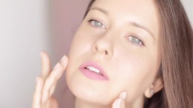 Güzel bir kadın yüzüne dokunuyor, yüz masajı çizgileri ile organik kozmetik krem sürüyor, parlayan sağlıklı cilt ve doğal cilt rutini, yaşlanmayı önleyen güzellik ve sağlıklılık.