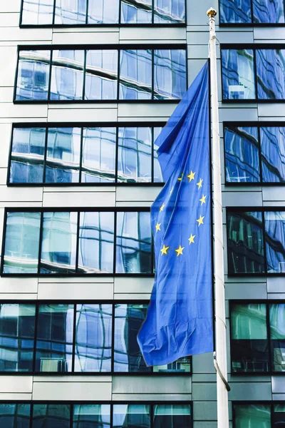Drapeau de l'Union européenne agitant devant un immeuble de bureaux d'entreprise moderne, symbole du Parlement européen, de la Commission et du Conseil — Photo