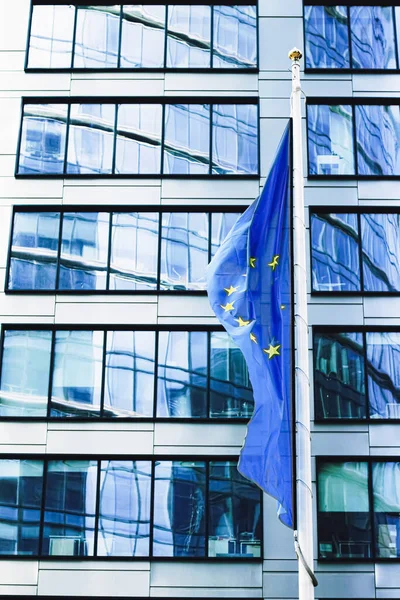 Drapeau de l'Union européenne agitant devant un immeuble de bureaux d'entreprise moderne, symbole du Parlement européen, de la Commission et du Conseil — Photo