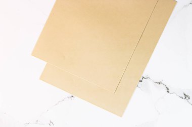 Beyaz mermer arka plan üzerine bej renkli A4 kağıtları ofis kırtasiyesi düz yatak, lüks markalaşma yatağı ve model kimlik tasarımı