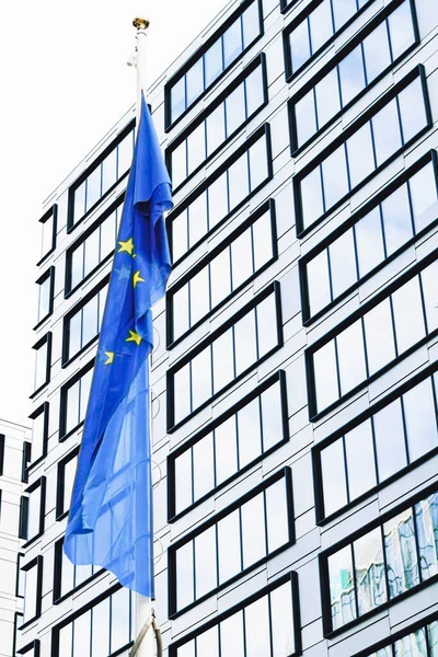 欧州連合の旗は、近代的な企業のオフィスビルの前で振って、 EU議会、委員会と理事会のシンボル — ストック写真