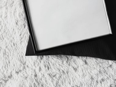 Poster fotokopisi olarak boş telif alanı olan ince ahşap çerçeve, siyah yastık ve yumuşak beyaz battaniye, düz arkaplan ve sanat ürünü