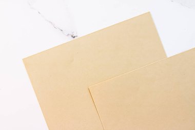 Beyaz mermer arka plan üzerine bej renkli A4 kağıtları ofis kırtasiyesi düz yatak, lüks markalaşma yatağı ve model kimlik tasarımı