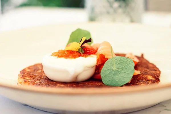 Panqueque de patatas fritas con caviar rojo, salmón y crema agria en un restaurante de lujo al aire libre en verano —  Fotos de Stock
