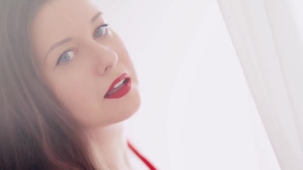 Hermosa mujer morena sonriendo, posando y bailando, luz brillante desde una ventana o puerta y cortinas blancas en el fondo, estilo de vida femenino y belleza natural — Vídeos de Stock