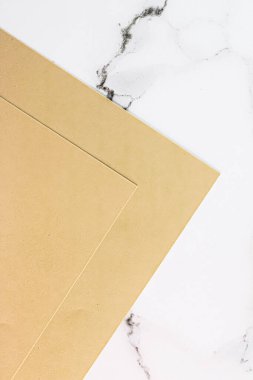 Beyaz mermer arka plan üzerine bej renkli A4 kağıtları ofis kırtasiyesi düz yatak, lüks markalaşma yatağı ve model kimlik tasarımı