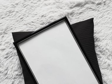 Poster fotokopisi olarak boş telif alanı olan ince ahşap çerçeve, siyah yastık ve yumuşak beyaz battaniye, düz arkaplan ve sanat ürünü