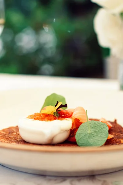 Panqueque de patatas fritas con caviar rojo, salmón y crema agria en un restaurante de lujo al aire libre en verano —  Fotos de Stock