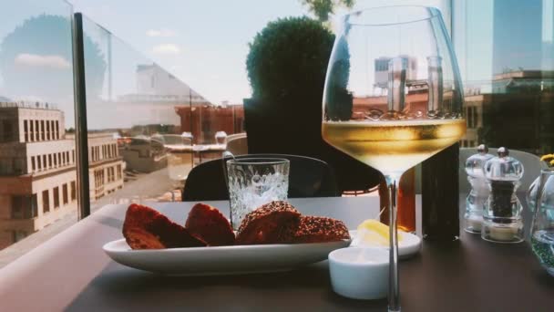 Glas witte wijn en eten in een restaurant buiten — Stockvideo