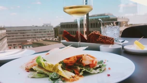 Cesar salát s krevetami a bílým vínem sklenice v luxusní střešní restauraci — Stock video