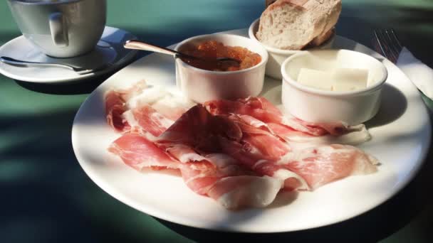 Kopje koffie, vers brood, jam en ham op tafel voor het ontbijt snack in de ochtend in de zomer buiten — Stockvideo