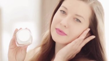 Doğal cilt bakımı rutini, güzel bir kadın gülümseyen ve elinde yüz nemlendirici kremi kavanozu olan sağlıklı cilt bakımı, lüks kozmetik ürünleri, sağlıklı insanlar ve güzellik tedavisi.