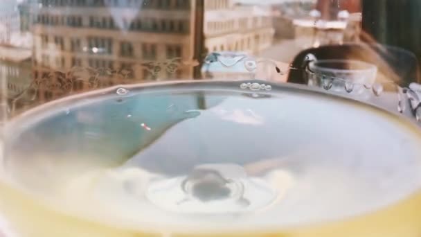 Makro av vitt vin i ett glas utomhus, stadsbild på bakgrunden — Stockvideo