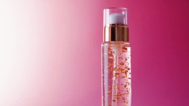 Pembe arka planda altın şişede cilt jölesi