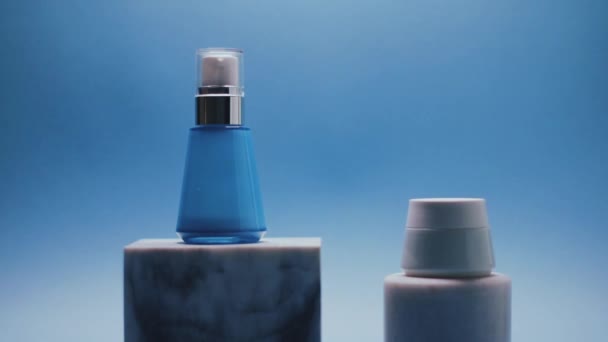 Бутылка сыворотки и банка крема для лица на голубом фоне, роскошные продукты по уходу за кожей, красота и косметика — стоковое видео