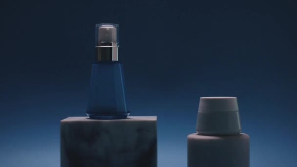 Пляшка сироватки та кремова банка для обличчя на синьому фоні, продукти розкоші, краса та косметика — стокове відео