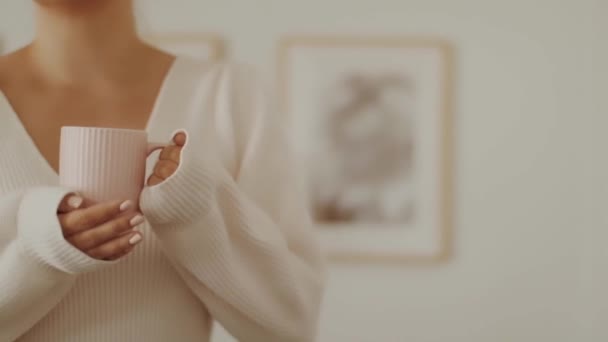 Женщина держит теплую кружку с чаем или кофе дома в холодном осеннем или зимнем сезоне — стоковое видео