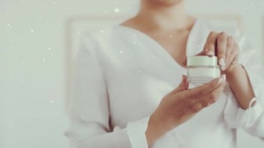 Kış mevsimi için cilt bakımı, yüz kremi kavanozu tutan kadın, düşen kar ve Noel simleri.