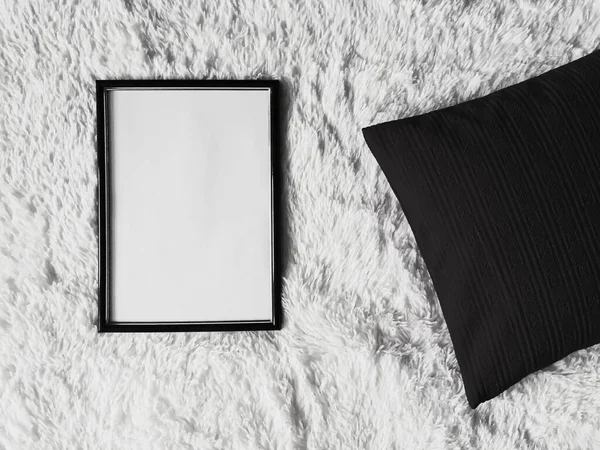 Tenký dřevěný rám s prázdným kopírovacím prostorem jako plakát fotografie tisk mokup, černý polštář polštář polštář a nadýchaná bílá přikrývka, ploché ležel na pozadí a umělecký výrobek — Stock fotografie