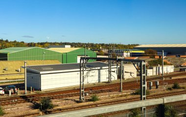 Railway tracks spanning across an industrial area, featuring warehouses and commercial buildings in a manufacturing and logistics setting