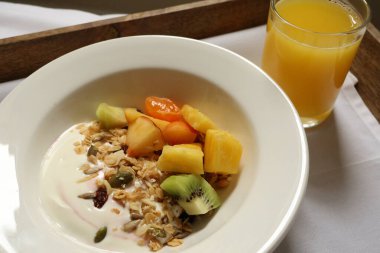 Tahta tepside sağlıklı bir yoğurt, tahıl gevreği, meyve ve portakal suyu servisi. Cotswold kırsal, İngiltere