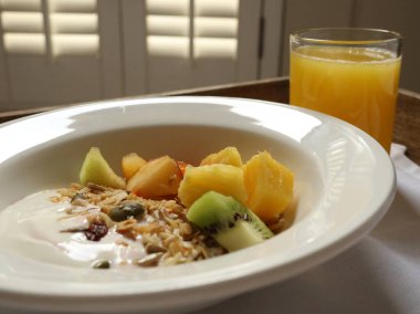 Bir kase yoğurtlu müsli, kabak çekirdeği, granola, taze meyve ve portakal suyu. Cotswold kırsal, İngiltere