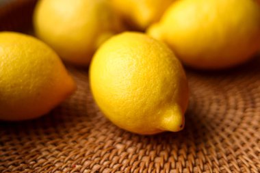 Sarı limonlar, sağlıklı beslenme, taze malzemeler ve doğal gıda kavramlarını vurgulayarak dokunmuş bir hasır yüzeyde toplandılar.