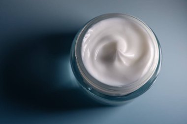 Beyaz losyon açık bir kozmetik kavanozunda düzgün bir şekilde dönüyor, doğal cilt bakımı, nemlendirici ve yaşlanmayı önleyici faydalar sağlıyor.