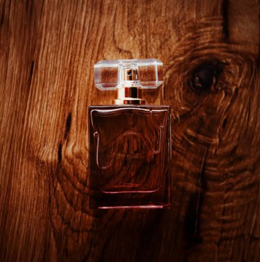 Doğal ahşap arka planda lüks bir koku içeren cam parfüm şişesi zarafet, güzellik ve aromatik hoşgörü çağrıştırıyor.