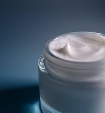 Cam bir kavanozu dolduran beyaz yüz kremi, pürüzsüz bir dokuyu ve üzerinde küçük bir zirveyi gösterir, güzellik ve cilt sağlığı kavramları için mükemmeldir.