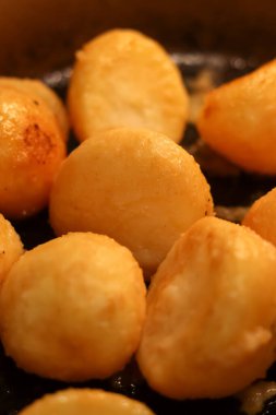 Koyu bir tavada pişen altın sarısı kızarmış patates, akşam yemeği için lezzetli ve rahatlatıcı bir garnitür.