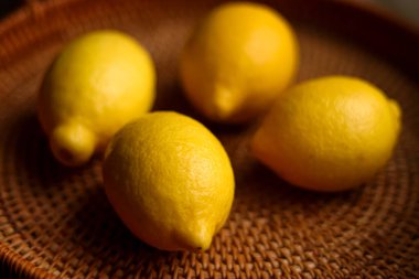 Dört olgun sarı limon kahverengi bir sepetin üzerinde dinleniyor taze, ekşi narenciye meyvesi, yiyecek ve sağlıklı besleniyorlar.
