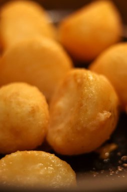 Çıtır çıtır ve yuvarlak patatesler tavada pişiyor, altın kahverengi dokularını ve lezzetli görünümlerini sergiliyorlar.