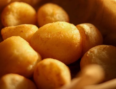 Yakından bakıldığında altın patates kroketleri, kırsal bir doku ve sıcak davetkar bir ışık sergiliyor, konforlu yiyecekleri temsil ediyor.