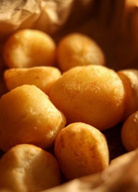 Lezzetli sıcak pao de queijo, Brezilya peynirli ekmek ruloları, taze pişmiş ve kağıt bir torba içinde yenmeye hazır.