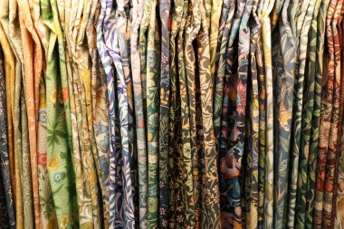 Klasik tekstil kumaşları çeşitli zarif çiçek ve botanik desenleri sergiliyor. Renk ve tasarımdan oluşan zengin bir duvar halısı oluşturuyor.