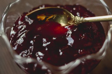 Temiz bir cam kasede, kalın, tatlı meyve reçeli. Süslü altın bir kaşık, kahvaltı veya tatlı için mükemmel.