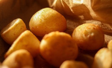 Kırış kırış kahverengi bir kesekağıdında altın rengi patates pufları. Kızarmış sıcak abur cubur ya da aperatif. Görüntüyü kapat