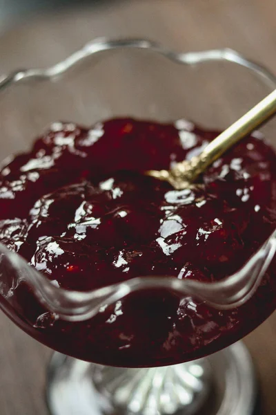 Dalgalı cam bir kasede altın kaşıkla reçel, kahvaltıda ya da tatlıda parlak kırmızı serpiştirilmiş, kırsal gurme natma natürmort, kapan