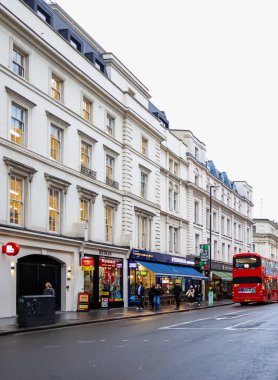 Londra, İngiltere, İngiltere 16 Aralık 2025: Londra caddesi insanlarla dolu ve kırmızı çift katlı bir otobüs dükkanları ve tarihi binaları geçiyor