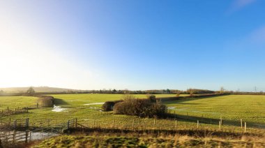 Oxfordshire kırsal kesiminde, durgun su, çitler ve sabah güneşinin altındaki çitlerin bulunduğu yeşil otlaklar huzurlu bir kış gününü betimliyordu.
